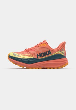 HOKA running shoe in coral and teal, featuring a mesh upper, padded collar, bold branding, and a textured sole with traction lugs.