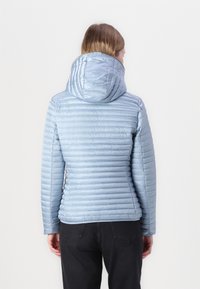 Lyseblå pufferjakke med hætte, der har et kviltet design og en glat, shiny tekstur. Bagfra ses let samling ved taljen.