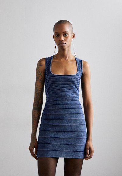 Rochie mini albastră cu dungi ondulate și decolteu pătrată, având un croi ajustat. Modelul poartă cercei lungi din argint.