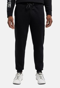 Sorte sweatpants med snoretræk i taljen, ribbede cuffs og sidelommer. Fremstillet af blødt stof, der har en glat tekstur.