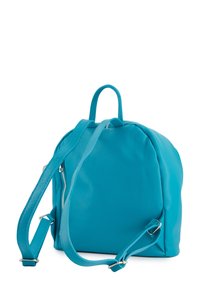 Sac à dos en cuir turquoise avec une forme arrondie, disposant de bretelles réglables, d'une poignée de transport en haut et d'une fermeture à glissière.