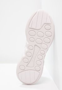 Ljust rosa sneakersula med texturerat gummi, cirkulära grepp och framträdande varumärke. Har en förstärkt tå och flexibelt kantdesign.