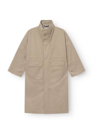 Beige lang frakk med høy krage, frontlommer med klaff, vide ermer med trykknapper og skjult frontåpning.