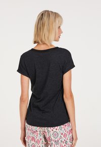 Top corto grigio scuro a maniche corte con vestibilità rilassata, scollo a cucitura piatta e texture morbida. Abbinato a pantaloni da pigiama con fantasia in più colori.