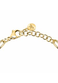 Bracciale in tono oro con segmenti di catena intrecciati, chiusura a morsetto e un'etichetta tonda con un design inciso a foglia.
