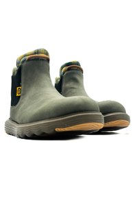 Botines de ante verde con panel lateral texturado negro y forro de tela a cuadros. Suela de goma con un patrón de olas. Detalle del logo de la marca en amarillo.