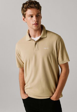 Beežist polo särk tekstuurse kangaga, millel on klassikaline krae, lühikesed varrukad ja vasakul rinnal peen logo.