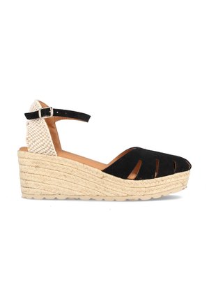 Sandalia de cuña de ante negro con diseño recortado, tira de tobillo trenzada y suela de yute natural. Tacón elevado y superficie texturizada.
