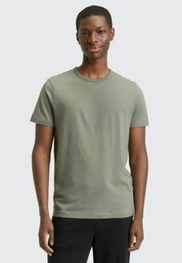 Oliwkowa koszulka z krótkim rękawem, wykonana z miękkiej bawełny, z okrągłym dekoltem, o luźnym kroju i gładkiej fakturze. Nadaje się do codziennego noszenia.