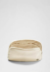 Kreminės spalvos maišelis su užtrauktuku, turintis vidinį tinklinį kišenę ir mažą logotipo etiketę priekyje. Lygus, matinės tekstūros.