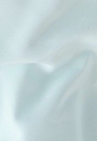 Gros plan sur un tissu tissé bleu clair avec des plis subtils et une surface finement texturée.