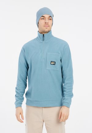Sudadera de forro polar azul claro con cuello de media cremallera y bolsillo frontal. Gorro de punto acanalado en un color a juego. Textura suave y diseño casual.