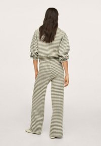 Zielona i beżowa, w kratkę, oversize'owa bluza oraz dopasowane, rozszerzane spodnie, wykonane z miękkiego materiału i z elastycznym paskiem.