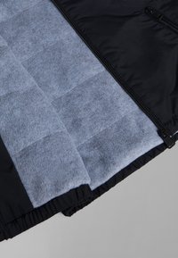 Black outer shell jacket with gray fleece interior, featuring quilted padding and a zippered front. Elasticated cuffs for fit.