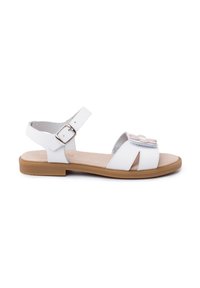 White sandal made of synthetic material, featuring a simple design with an adjustable ankle strap, floral accent, and a tan outsole.