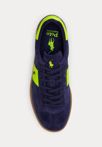 Σκουρό μπλε σουέντ αθλητικό παπούτσι με φωτεινές κίτρινο-πράσινες λεπτομέρειες, καφέ σόλα, λογότυπο Polo Ralph Lauren στη γλώσσα, στη πλευρά και στην εσωτερική σόλα.