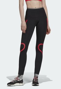Czarne legginsy z czerwonymi akcentami i sercowymi wzorami na kolanach, z wysokim stanem i miękkim, elastycznym materiałem.