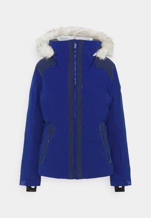 Sininen laskettelutakki, jossa on karvareunuksinen huppu, vetoketjulliset taskut ja kontrastiväriset tummansiniset yksityiskohdat. Siinä on etuvetoketju ja säädettävät kiristysnauhat.