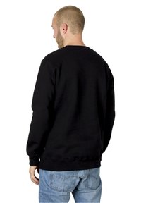 Sort sweatshirt med lange ærmer, ribbede manchetter og kant, design med rund hals, lavet af et blødt materiale, parret med lyseblå jeans.