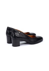 Chaussures à talon bas en cuir noir avec texture crocodile sur le talon et petits clous dorés sur le côté, doublure intérieure marron.