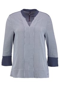 Koszula w paski w niebiesko-białym kolorze, z długim rękawem i dekoltem w serek, z kontrastującymi granatowymi paskami przy mankietach i luźnym krojem. Materiał wydaje się lekki.