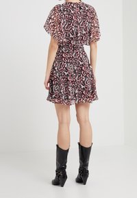 Robe à manches courtes, à volants, en tissu transparent avec un motif ondulé noir, blanc et rouge. Associée à des bottes noires à talons, montantes jusqu'aux genoux.