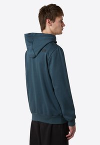 Hoodie in teal, met een zachte stof, geribbelde manchetten en tailleband. Logo weergegeven op de schouder aan de achterkant.