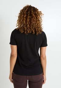 Camiseta negra de manga corta con cuello redondo, hecha de suave tela de algodón, vista desde la parte posterior, con un diseño ajustado.