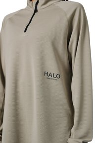 Helle beige Viertelreißverschluss-Pullover mit strukturiertem Muster, ausgestattet mit schwarzem Reißverschluss und Logo auf der linken Seite. Lange Ärmel mit entspannter Passform.