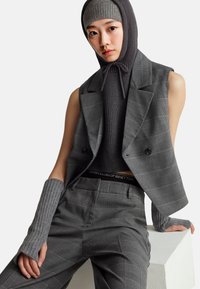 Szary dopasowany kamizelka i pasujące w kratkę spodnie z prążkowanym ciemnoszarym topem oraz rękawiczkami bez palców, z logo w pasie.