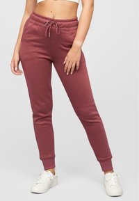 Bordeauxfarbene Sweatpants mit elastischem Taillenbund, Kordelzugdetails und schmal zulaufenden Beinen. Hergestellt aus weichem Stoff, mit Seitentaschen und gerippten Bündchen.
