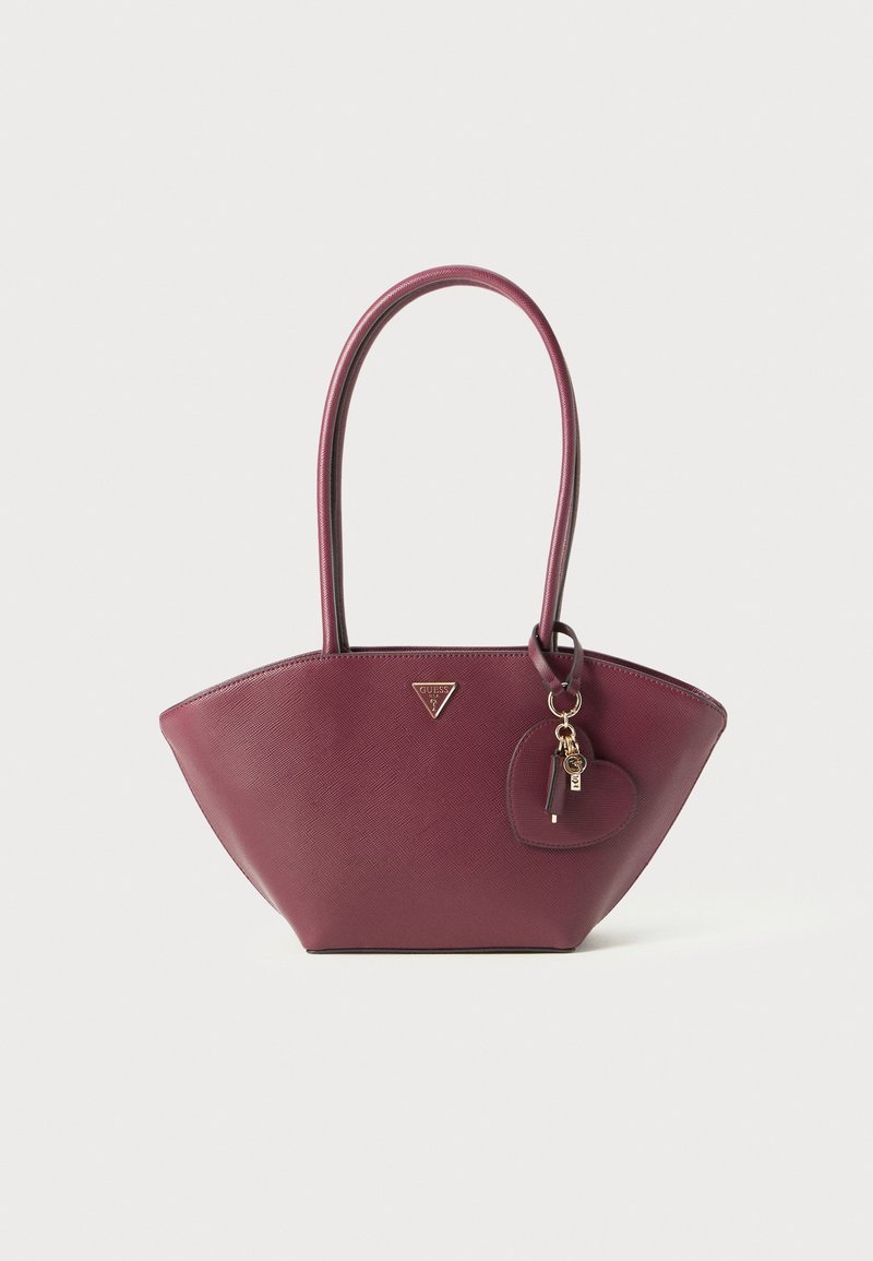 Sac à main en cuir bordeaux avec longues anses, logo triangulaire Guess et breloque en forme de cœur avec clé et étiquette dorées.