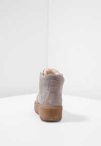 Szare zamszowe botki do kostki z teksturowaną, brązową podeszwą, miękkim wnętrzem i zaokrąglonym noskiem, z dyskretnym logo po boku.