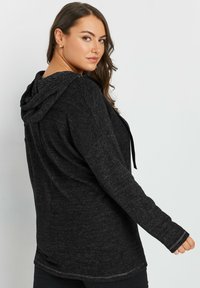 Mustapuhvemekko, jossa on rento leikkaus ja pehmeä kangas. Ominaisuuksina pitkät hihat ja hienovaraisesti teksturoitu pinta.