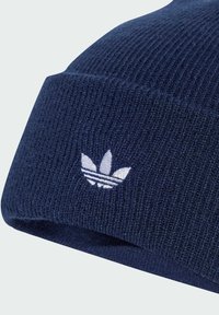 Mornarska rebrasta pletena kapa s bijelim izvezenim Adidasovim trefoil logotipom i detaljima s tri pruge. Mekana tekstura, prilagođen dizajn.