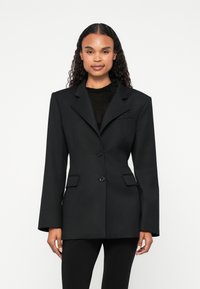 Musta bleiser, pikkade varrukatega, kraedega, ühe nupuga ja kahe eesmine taskuga, valmistatud struktureeritud kangast, istuv lõige.