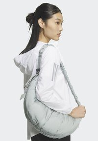 Borsa color grigio chiaro, di forma rotonda, con una texture morbida e dettagli arricciati. Indossata a tracolla con una cinghia regolabile.