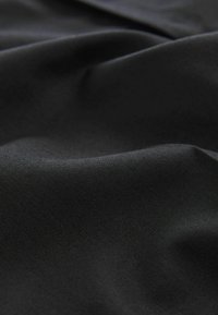Schwarzer Stoff mit einer glatten Textur und einem subtilen Fischgrätmuster. Das Material wirkt leicht und ist sanft zerknittert.