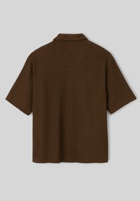 Chandail marron à manches courtes avec une texture côtelée, doté d'un col classique et d'une coupe décontractée. Élégamment simple, sans motifs ni accessoires visibles.
