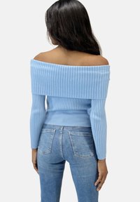 Helles blaue, schulterfreie, gerippte Sweater mit langen Ärmeln, enganliegendem Schnitt und strukturiertem Stoff, kombiniert mit hellblauen Jeans.