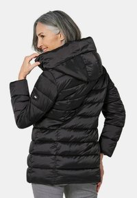 Schwarze Daunenjacke mit Kapuze, ausgestattet mit einem gesteppten Design und gerippten Bündchen. Glattes, glänzendes Material mit einer taillierten Silhouette und Seitentaschen.