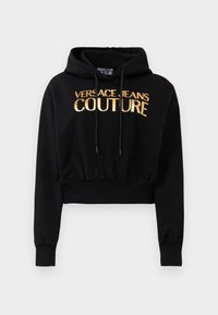 Svart cropped hettegenser med snor og gull "VERSACE JEANS COUTURE"-tekst på forsiden.