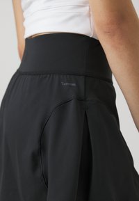 Skort sportivo nero con una fascia in vita ampia e pieghe nascoste. Realizzato in tessuto leggero e traspirante con etichetta "CLIMACOOL".