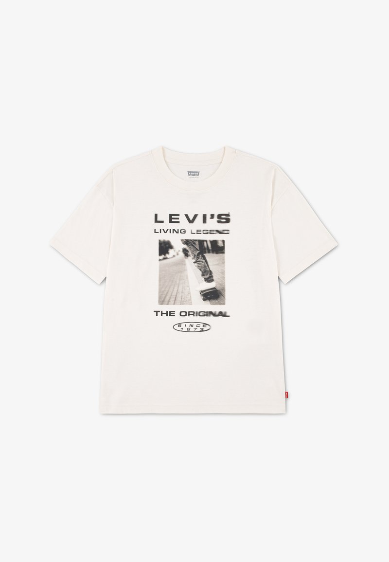 Λευκό μπλουζάκι Levi's με μαύρο κείμενο "LEVI'S LIVING LEGEND THE ORIGINAL SINCE 1873" και ασπρόμαυρη φωτογραφία ενός ατόμου που κάνει σκέιτμπορντ.