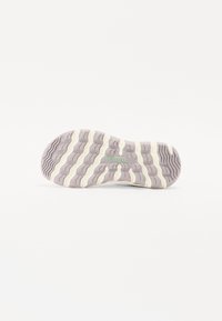 Trail shoe outsole in light purple with textured grip patterns, featuring a wavy design and "MERRELL" logo in green.