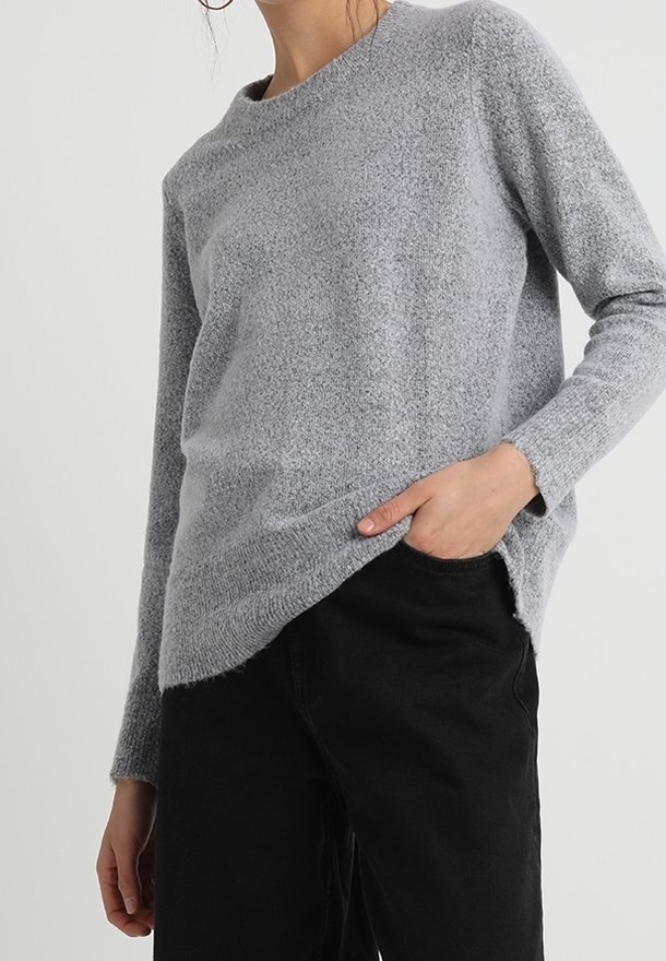 Maglione grigio strutturato con scollo rotondo e spacchi laterali, abbinato a pantaloni neri. Il maglione ha maniche lunghe e una vestibilità comoda.
