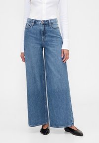 Dolge kavbojke iz jeansa v svetlo modri barvi z visokim pasom, sprednjimi žepi in klasično zasnovo s petimi žepi. Zožen rob z minimalnim šivanjem.