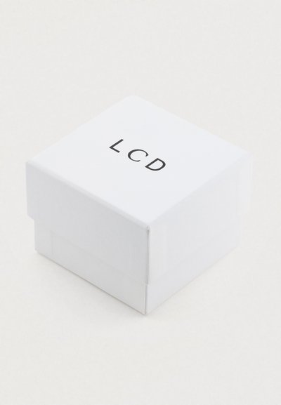 Bela papirnata škatla z zložljivim pokrovom, na vrhu črno napisana beseda "LCD". Gladek površinski material, kvadratna oblika, minimalističen dizajn.