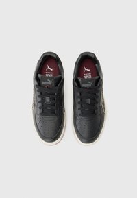 Sneaker in pelle nera con punta perforata, lacci tondi e pannello laterale testurizzato. Fodera interna bordeaux e suola in gomma bianca.