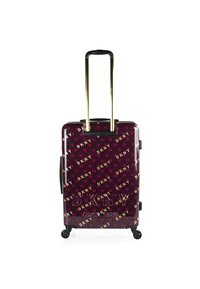 Maleta rígida con ruedas en color burdeos con un patrón dorado del logo de DKNY, asa retráctil, detalles en negro y cuatro ruedas multidireccionales.